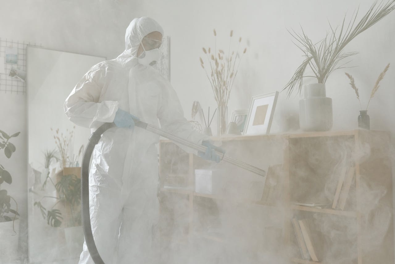 Home Individual in protective suit and mask sanitizing a room with smoke fumigation.