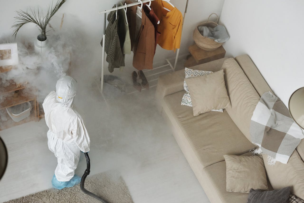 Home Professional in protective gear sanitizing a modern living room with a fumigation machine.