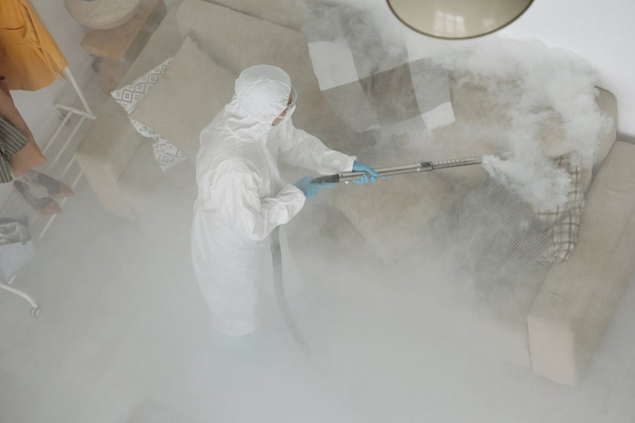 Home Technician in protective gear sanitizing a living room with smoke fumigation.